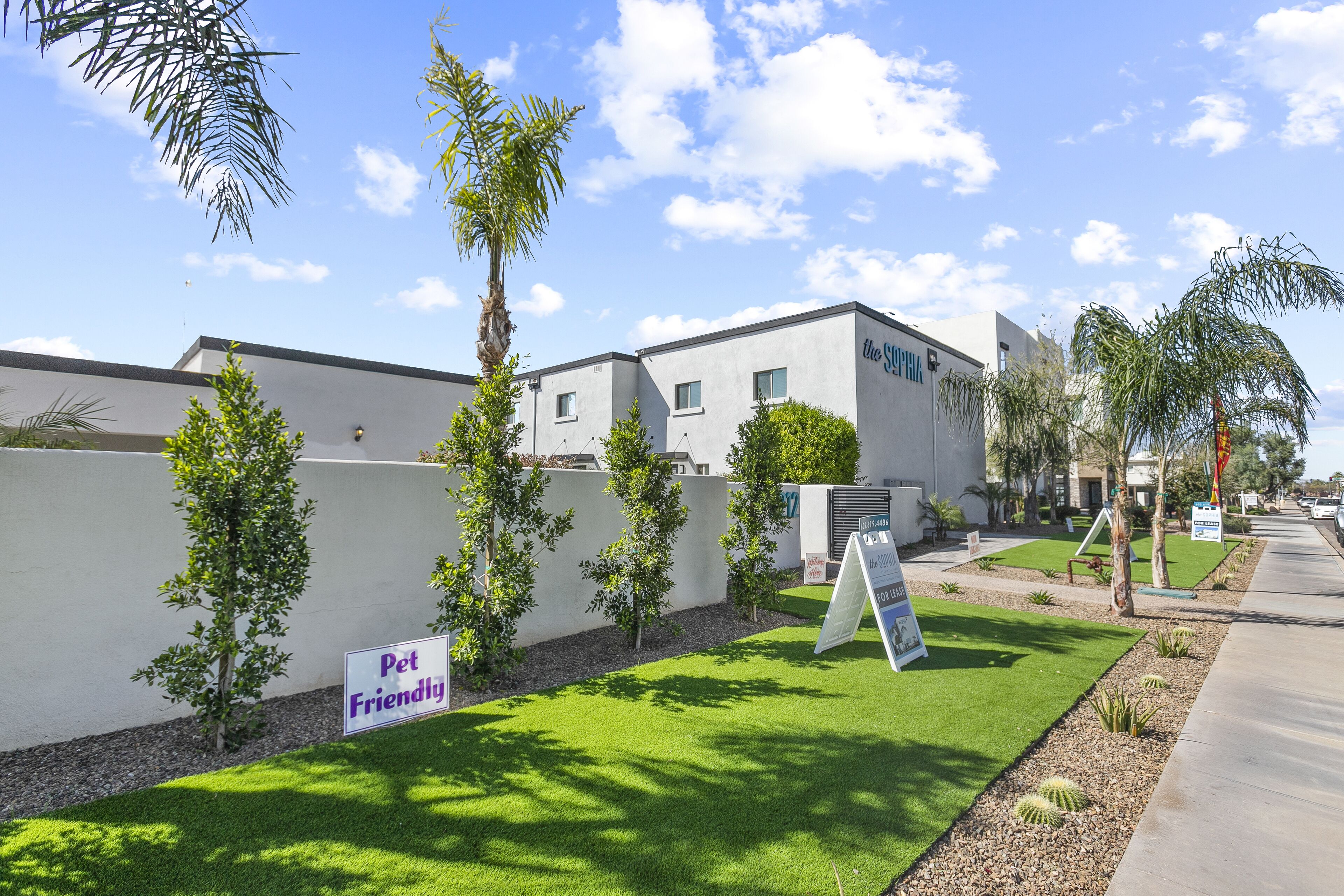 A pet-friendly building with a well-maintained lawn and small trees.