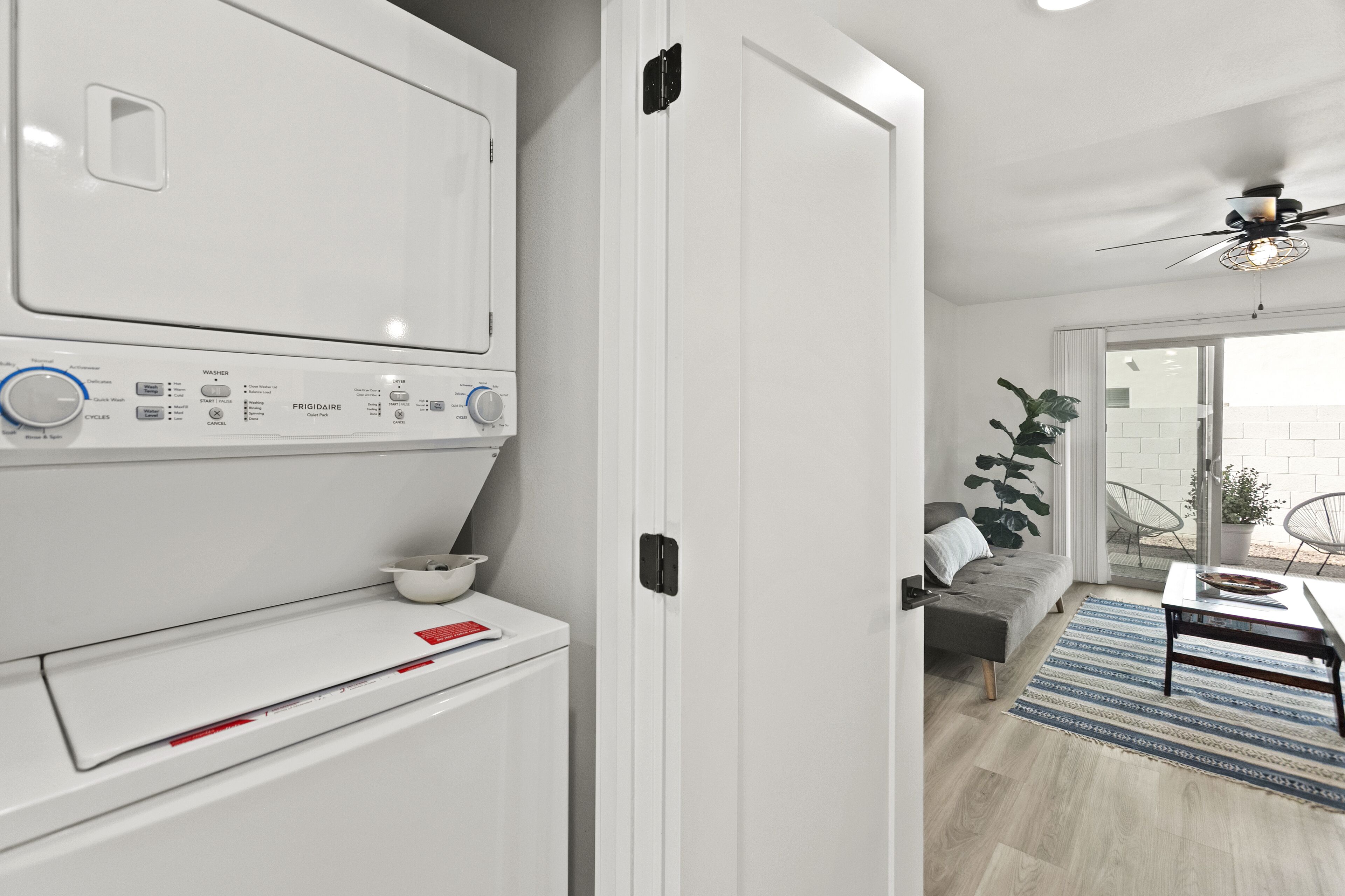 Une cuisine moderne équipée d’un lave-linge et d’un sèche-linge intégrés, d’un canapé gris et d’un coin repas avec une table et des chaises.
