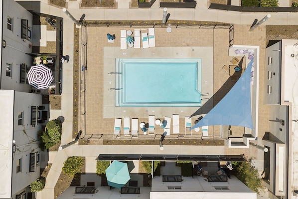 An aerial view of a rooftop pool area with lounge chairs, a pool, and a covered seating area. - Sophia (Scottsdale)