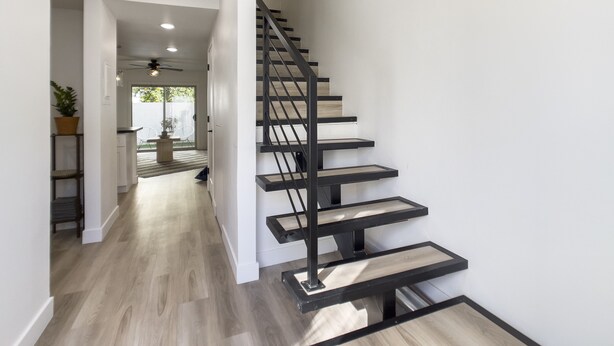 A modern staircase with a black metal railing and wooden steps leading to a second-floor landing. - Sophia (Scottsdale)