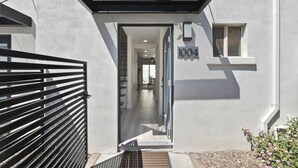 A modern building entrance with a metal gate, a number '1004' sign, and a small window. - Sophia (Scottsdale)