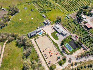 Une vue aérienne d’un complexe comprenant un vaste terrain découvert, une zone délimitée par une clôture et équipée de cibles, ainsi qu’un ensemble de bâtiments comprenant plusieurs structures.