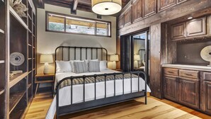 A bedroom with a metal bed frame, wooden flooring, and built-in shelving. - 15 Acre Luxury Estate | VIP Experience (Paso Robles)