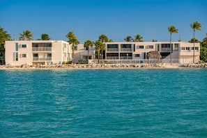 A beachfront hotel with multiple floors, balconies, and a pool area.