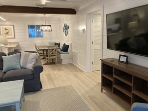 A modern living room with a sofa, coffee table, TV, and a dining area with a table and chairs.