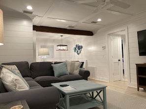 A modern living room with a gray sofa, a small table, and a television.