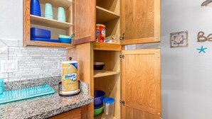 A kitchen with wooden cabinets, a granite countertop, and various kitchen items.