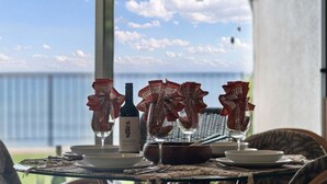 Ein Esstisch mit Wein, Gläsern und Geschirr, mit Blick auf ein Gewässer.