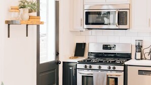 A modern kitchen with white cabinets, a stainless steel stove, a microwave, and a coffee maker. - Four Bed Family Stay. Near Sight and Sound. Hot Tub. Full Kitchen.  (Lancaster)