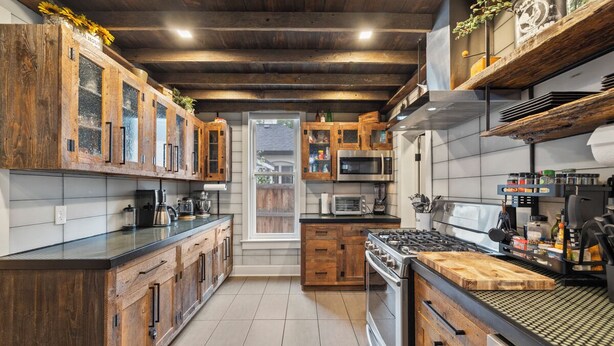 A modern kitchen with wooden cabinets, a large stove, and a microwave. - Uniquely Modern Old Town Gem with Hot Tub (Fort Collins)