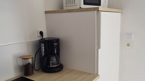 A compact kitchen with a microwave, coffee maker, and a small refrigerator.