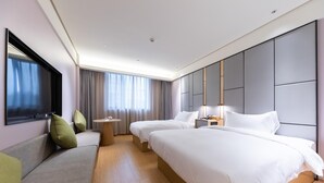 A hotel room with two beds, a sofa, a TV, and a bedside table with a lamp. - Ji Hotel (Huzhou)