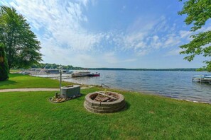 Relax by the serene lake with a fire pit and lush surroundings.