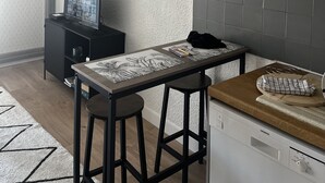 Eine moderne Küche mit schwarzem Arbeitsplatz, zwei Barhocker, einem Fernseher und einem Siemens Geschirrspüler.