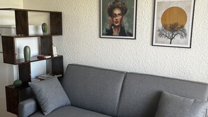 Ein modernes Wohnzimmer mit einem grauen Sofa, einem kleinen Couchtisch und einem Bücherregal.