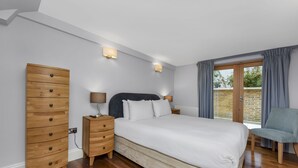 Un dormitorio con una cama grande, mesitas de noche de madera, un armario y una silla.