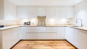 Una cocina moderna con armarios blancos, suelo de madera y estufa integrada.