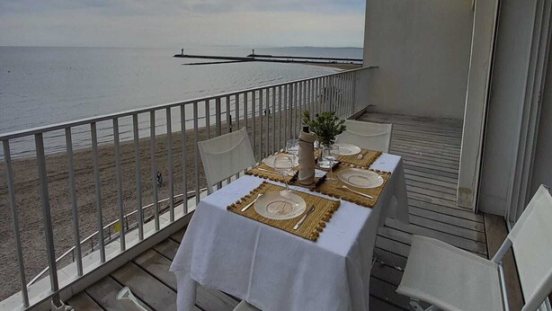 A terrace with a table set for two, overlooking a beach and the sea. - WATERFRONT APARTMENT FACING THE SEA (Agde)