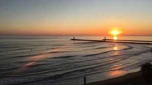 A sunset over a calm sea with a pier extending into the water. - WATERFRONT APARTMENT FACING THE SEA (Agde)