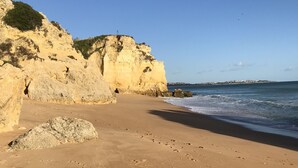 A coastal beach with sandy shores, rocky cliffs, and a clear blue sky. - Holiday house with big roof terrace pool and sea view (Porches,Lagoa)