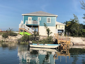 Una casa de dos pisos con balcón, muelle y un bote.