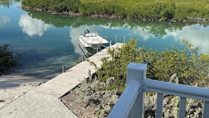A boat docked at a wooden pier with a clear view of a calm river and surrounding greenery.