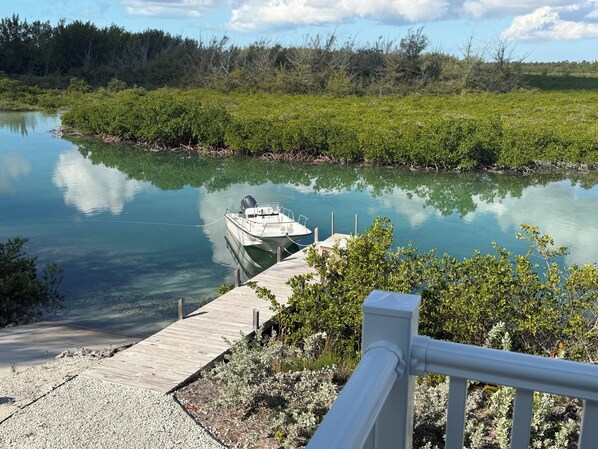 A boat docked at a wooden pier with a clear view of a calm river and surrounding greenery.