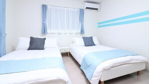 A bedroom with two beds, a window with curtains, an air conditioning unit, and a wall with a blue stripe. - HG Cozy Hotel (Neyagawa)