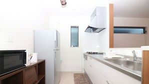 A compact kitchen with a microwave, refrigerator, stove, and sink. - HG Cozy Hotel (Neyagawa)
