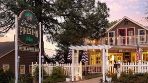 Ett hotell med en veranda, en skylt med texten ”Prescott Pines Inn” och ett vitt staket.