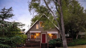 A lodge with a red door, a wooden porch, and a satellite dish.
