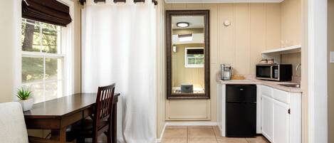 A compact kitchen with a dining table, chairs, a microwave, and a refrigerator.