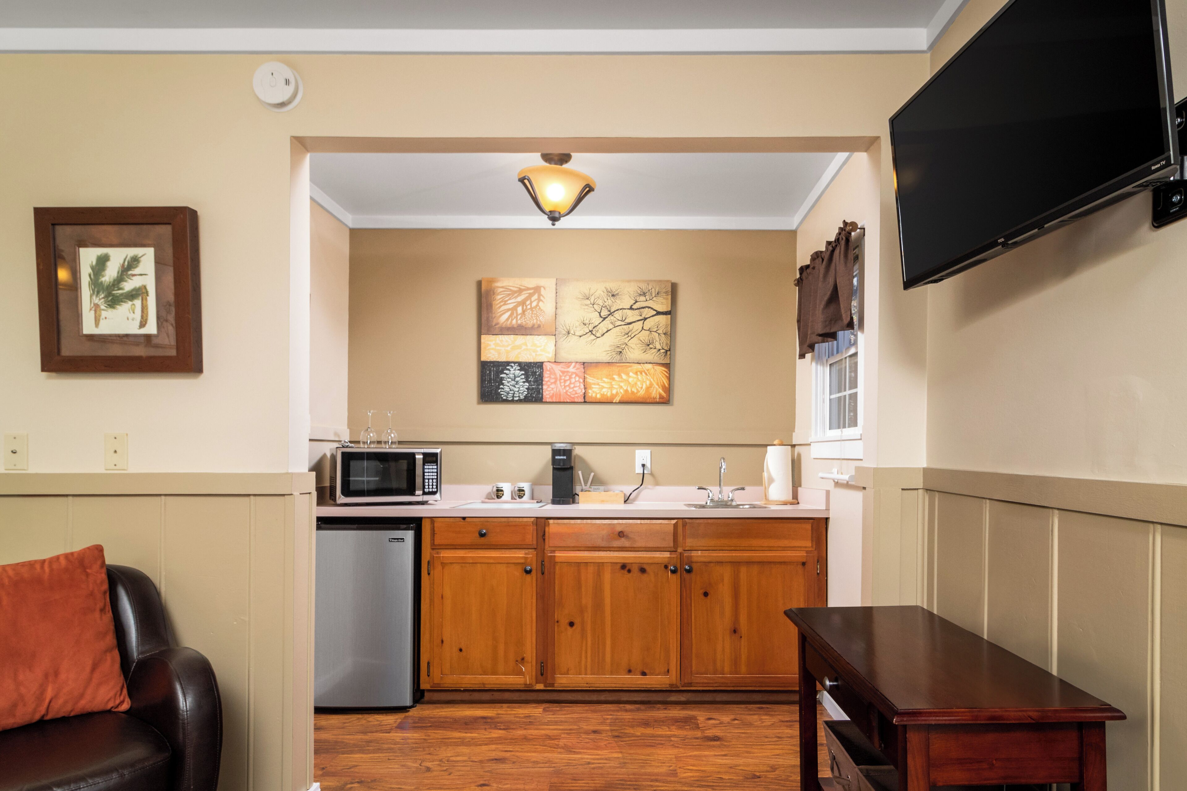 A compact kitchen with wooden cabinets, a microwave, and a sink.