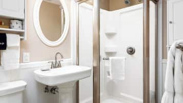 A bathroom with a white sink, a mirror, and a glass-enclosed shower.