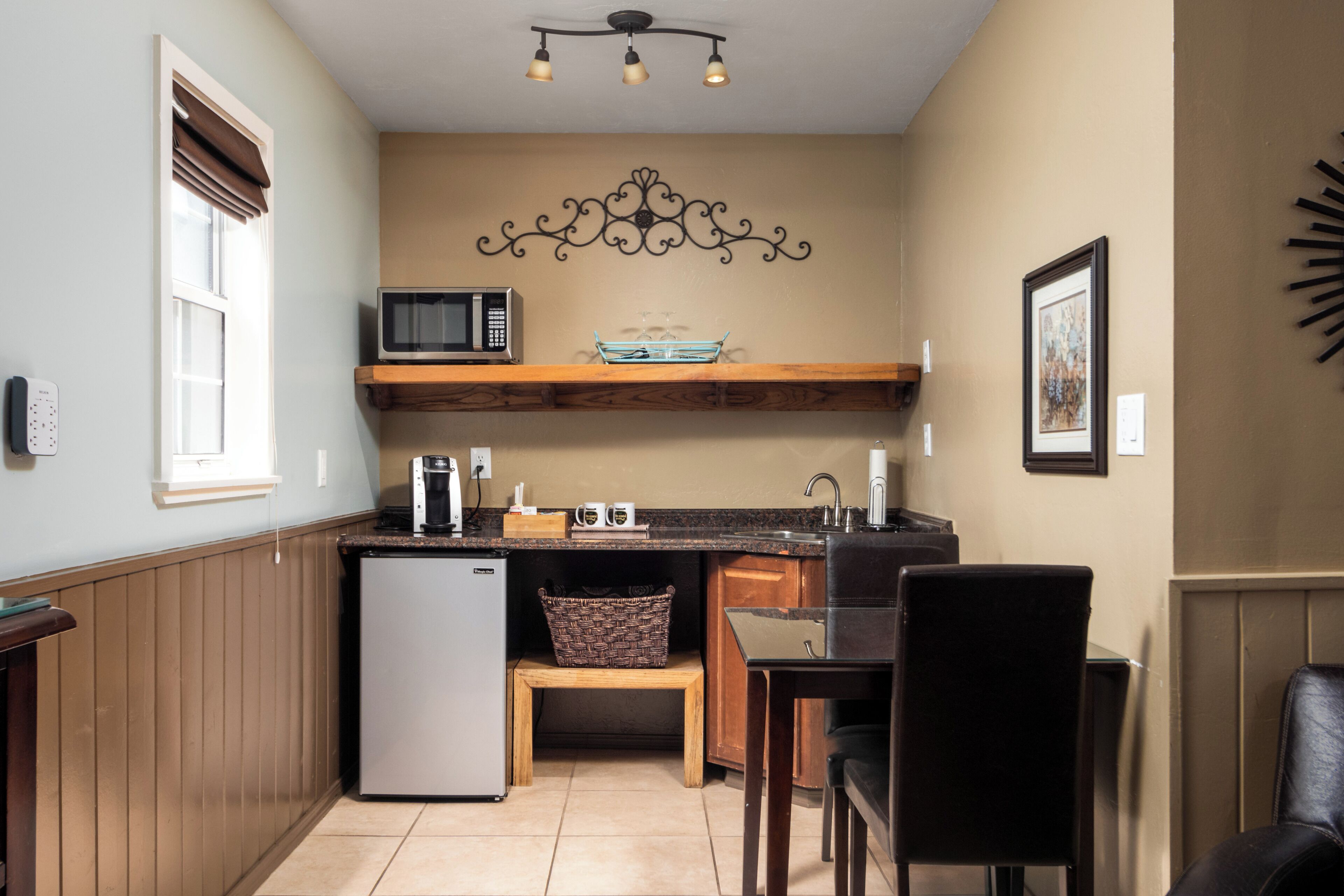A compact kitchen with a refrigerator, microwave, and wooden countertop.
