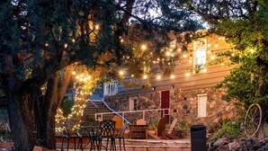 A stone building with a wooden deck, outdoor seating, and string lights.