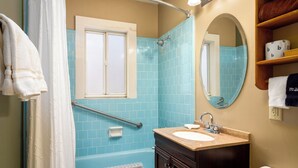 A bathroom with a bathtub, a sink, a mirror, and a shower area.