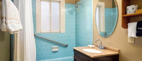 Un baño con bañera, lavabo, espejo y zona de ducha.