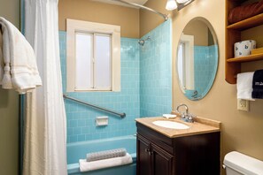 A bathroom with a bathtub, a sink, a mirror, and a shower area.
