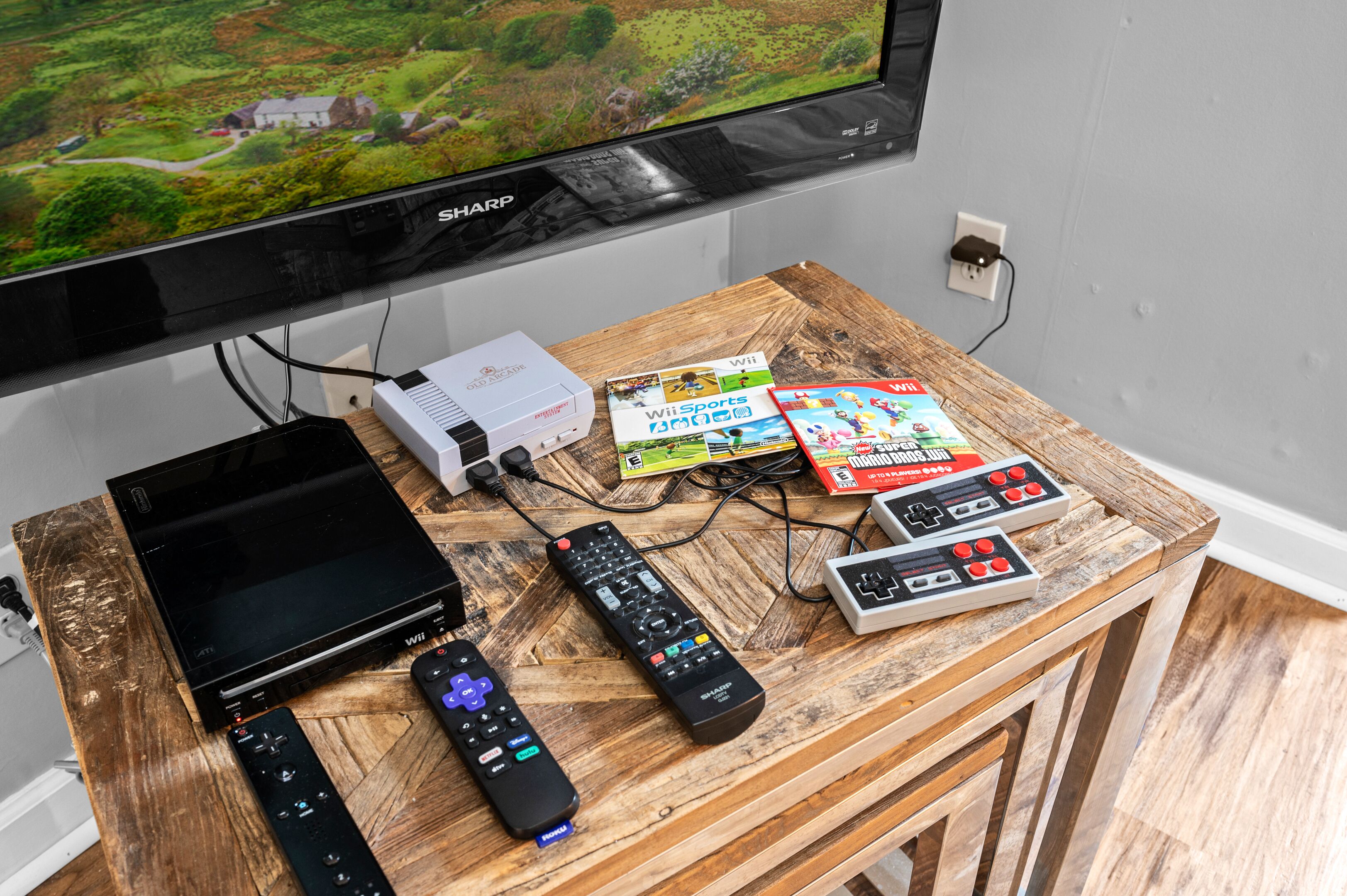 A wooden table with a television, a Wii console, and various game controllers.