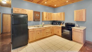 A kitchen with wooden cabinets, a black refrigerator, a microwave, and a stove. - Spacious Lodge on 40 Acres! (Cherryvale)