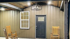 A covered outdoor area with two rocking chairs, a door, and a window. - Spacious Lodge on 40 Acres! (Cherryvale)