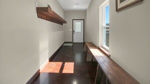 A hallway with wooden benches, a wooden shelf, and a framed picture on the wall. - Spacious Lodge on 40 Acres! (Cherryvale)
