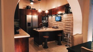 A modern kitchen with a central island, stainless steel appliances, and a brick accent wall. - COLONIAL HOUSE WITH CONTEMPORARY TOUCHES 7 ROOMS WITH TERRACE AND 2 SMALL POOLS (cartagena)