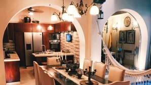 A modern kitchen with stainless steel appliances, a dining area with a large table and chairs, and a unique arched mirror. - COLONIAL HOUSE WITH CONTEMPORARY TOUCHES 7 ROOMS WITH TERRACE AND 2 SMALL POOLS (cartagena)