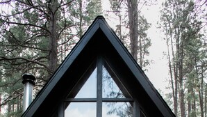 A cabin with a triangular roof, large windows, and a chimney.