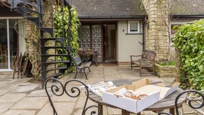 A patio with a table, chairs, and a box of pastries. There are benches and a staircase with vines. - Sandford Meadow Guest House (Oxford)