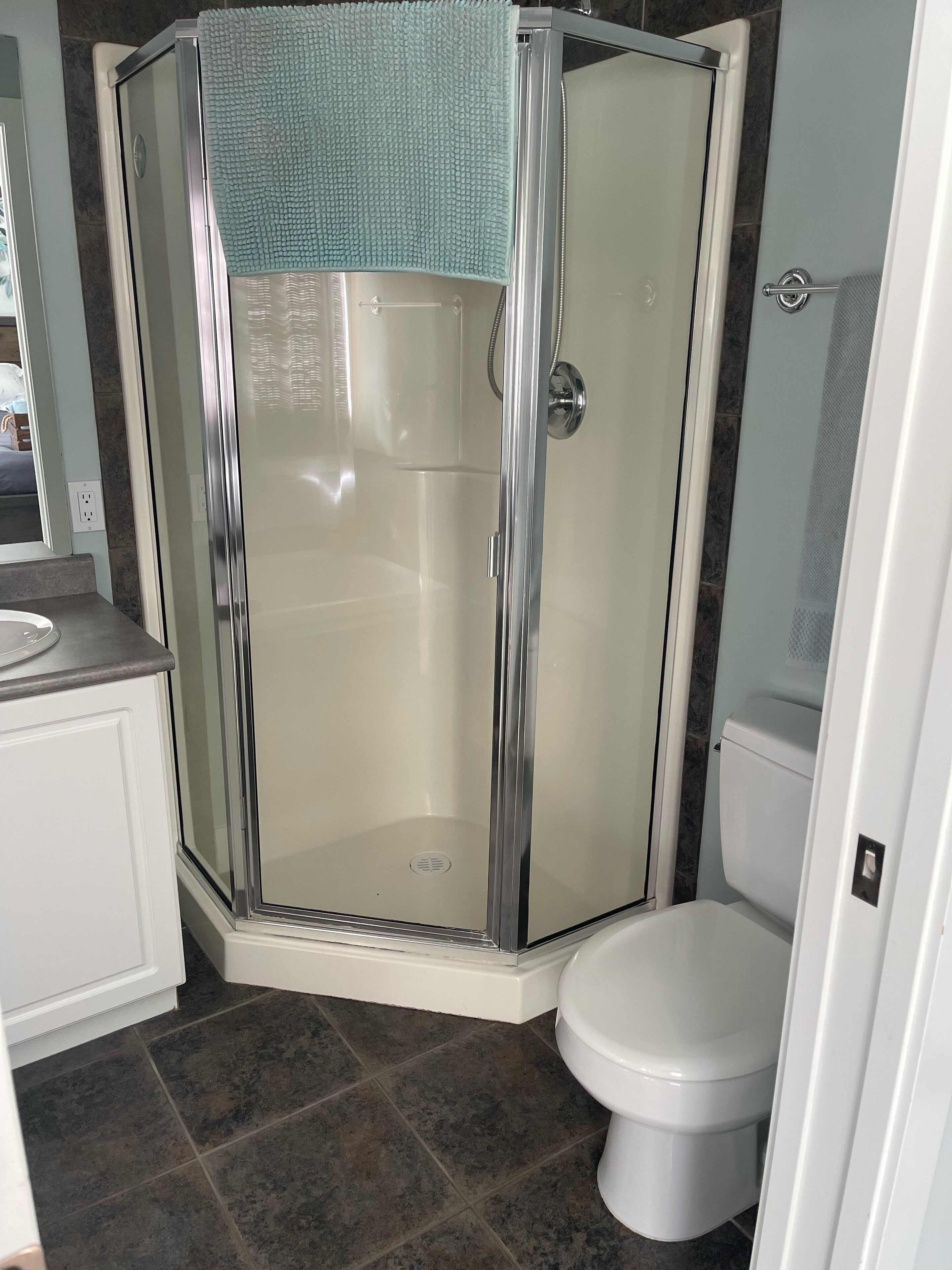 Un baño moderno con ducha envuelta en vidrio, inodoro blanco y encimera con lavabo.