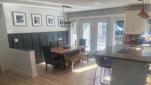 A modern kitchen with a wooden dining table, black chairs, and a built-in island with a sink.
