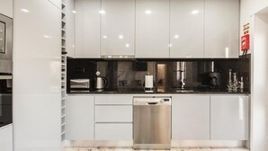 A modern kitchen with white cabinets, a black countertop, and stainless steel appliances.